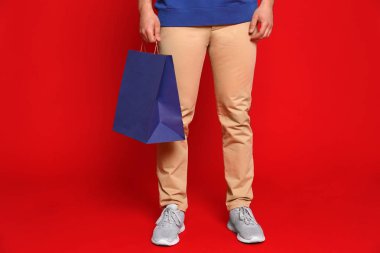 Kırmızı arka plan üzerinde kağıt torba ile genç adam, closeup