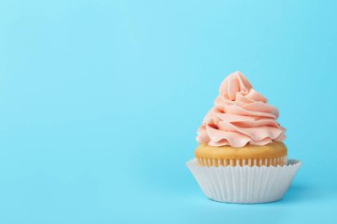 Açık mavi arka planda krem ile lezzetli cupcake, metin için alan