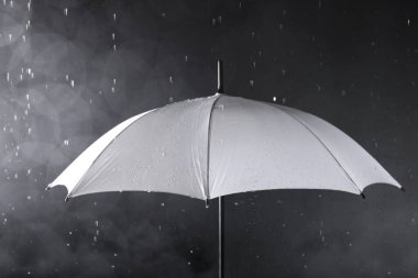 Koyu arka planda yağmur altında Beyaz şemsiye