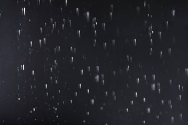 Karanlık arka plana karşı düşen yağmur damlaları