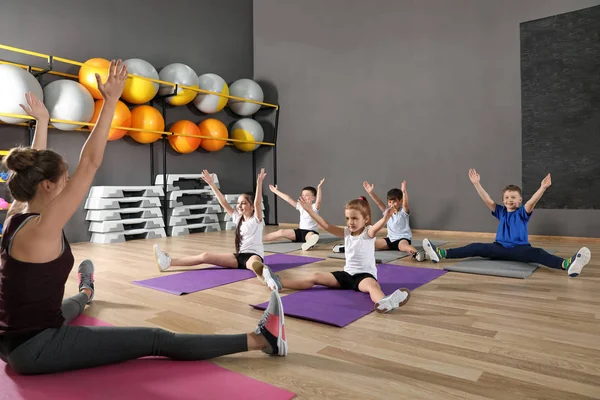 Cute little children and trainer doing physical exercise in school gym. Healthy lifestyle — Stock Photo, Image