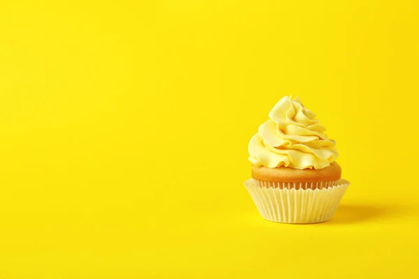 Smakelijke cupcake met crème op gele achtergrond, ruimte voor tekst — Stockfoto
