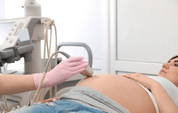 Giovane donna incinta sottoposta a ecografia in clinica moderna, vista da vicino — Foto Stock