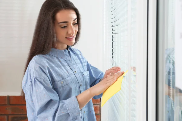 Mooie vrouw schoonmaken raam jaloezieën met Rag binnenshuis — Stockfoto