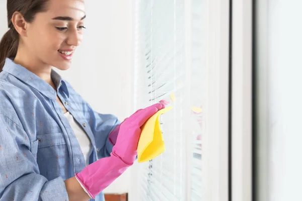 Schöne Frau putzt Jalousien mit Lappen drinnen, Nahaufnahme — Stockfoto