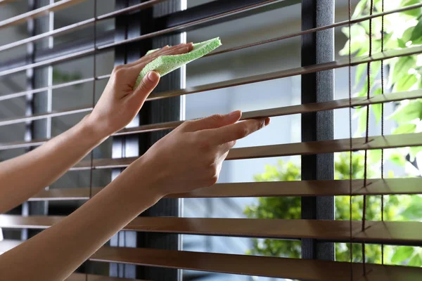 Woman wiping window blinds with rag indoors, closeup. Space for text — Stock Photo, Image