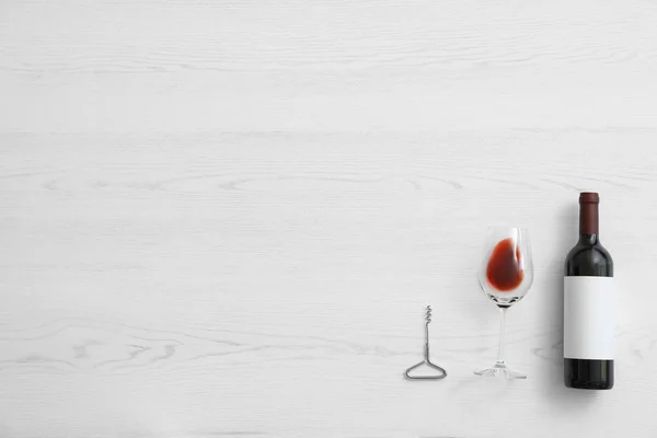 Composição plana com garrafa de vinho e vidro elegante sobre fundo de madeira branca. Espaço para texto — Fotografia de Stock