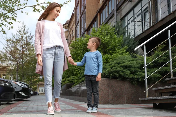 Счастливые ребенок и мать держатся за руки на улице, вид с низкого угла. Семейные выходные — стоковое фото