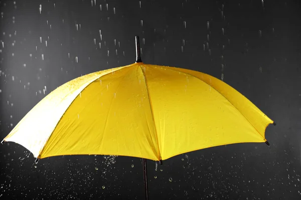 Guarda-chuva brilhante sob chuva no fundo escuro — Fotografia de Stock
