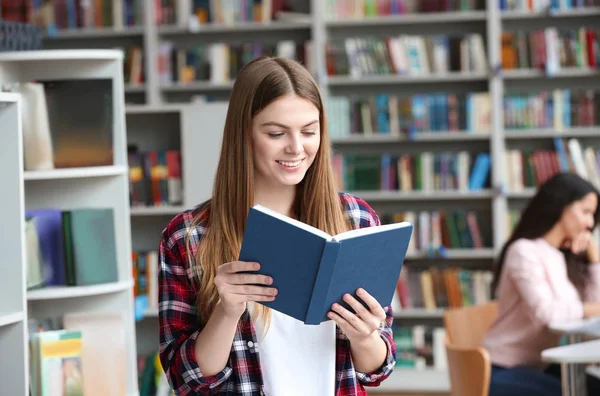 Jovem mulher bonita leitura livro na biblioteca — Fotografia de Stock