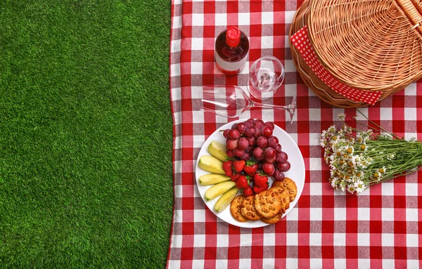 Composition à plat avec panier pique-nique et produits sur couverture à carreaux en plein air, espace pour le texte — Photo