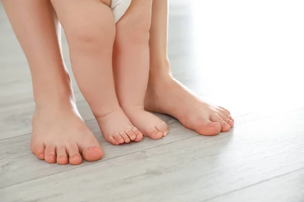 Mother and her baby standing on floor, closeup of legs — Stock Photo, Image