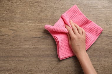 Mutfak havlusuyla ahşap masayı silen kadın, üst manzara. Metin için boşluk