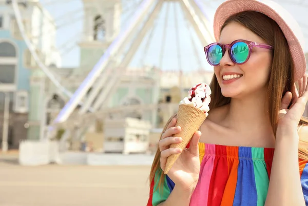 Joven mujer feliz con cono de helado en el parque de atracciones. Espacio para texto — Foto de Stock