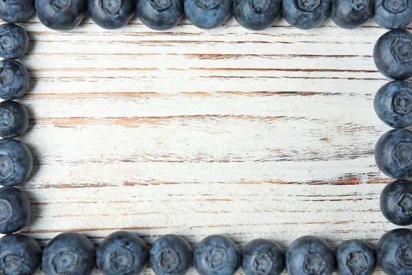 Рамка зі свіжою чорницею на білому дерев'яному столі, вид зверху. Простір для тексту — стокове фото