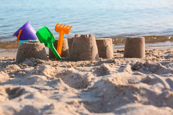 Piccole figure di sabbia e giocattoli di plastica sulla spiaggia vicino al mare — Foto Stock