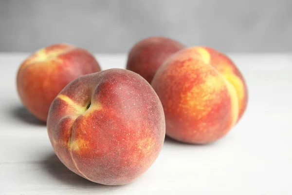 Fresh juicy peaches on white wooden table