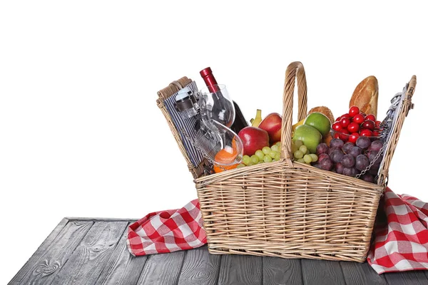 Wicker picknickkorg med vin och olika produkter på träbord mot vit bakgrund, utrymme för text — Stockfoto