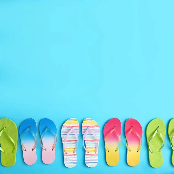 Diferentes chanclas y espacio para texto sobre fondo azul, plano. Accesorios de playa de verano —  Fotos de Stock