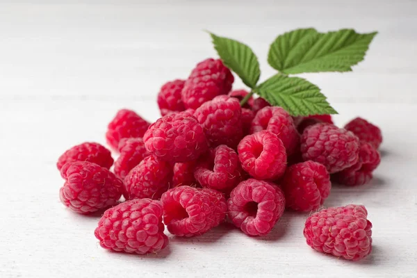 Delicious fresh ripe raspberries with leaves on white wooden table, closeup view — Stock Photo, Image