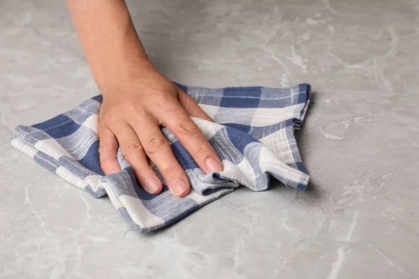 Жінка витирає мармуровий стіл з кухонним рушником, крупним планом — стокове фото