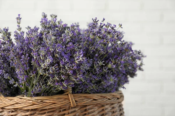 Ramo de flores de lavanda fresca en cesta contra la pared de ladrillo blanco, vista de primer plano —  Fotos de Stock