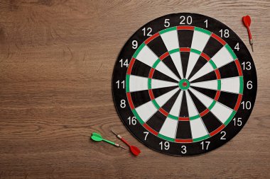 Ahşap arka plan üzerinde renk okları ile dart tahtası, üst görünüm. Metin alanı