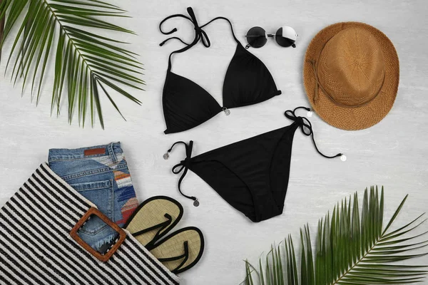 Composizione flat lay con costume da bagno nero e accessori da spiaggia su fondo marmo grigio — Foto Stock