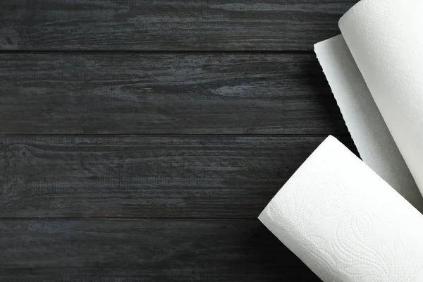 Rollos de toallas de papel sobre mesa de madera negra, vista superior. Espacio para texto — Foto de Stock
