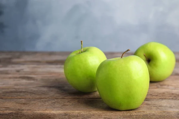 Pommes vertes mûres fraîches sur table en bois sur fond bleu, espace pour le texte — Photo