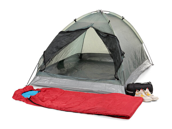 Comfortable grey camping tent with red sleeping bag and sneakers on white background