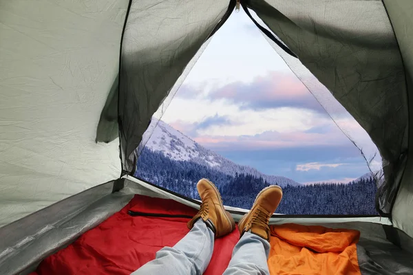 Primer plano del hombre en la tienda de campaña con sacos de dormir en la colina nevada, vista desde el interior — Foto de Stock