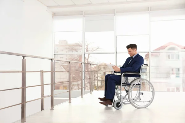 Jonge zakenman in een rolstoel met behulp van Tablet in de buurt venster binnenshuis — Stockfoto