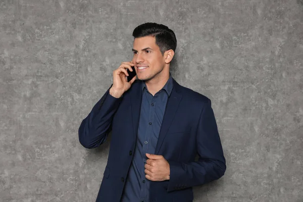 Retrato de homem de negócios falando ao telefone contra fundo cinza — Fotografia de Stock