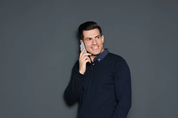 Retrato de homem bonito falando no telefone contra fundo cinza — Fotografia de Stock
