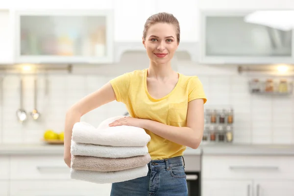 Mulher segurando toalhas limpas dobradas na cozinha. Dia de lavandaria — Fotografia de Stock