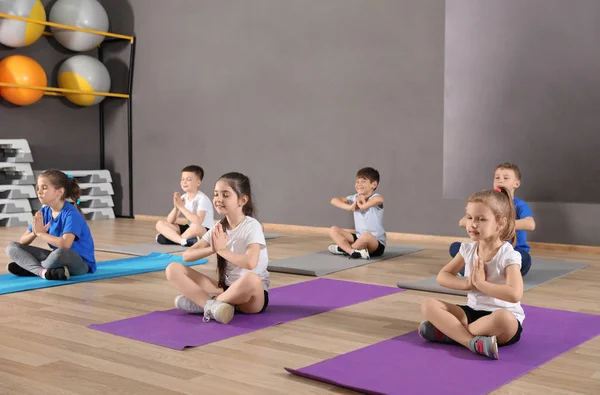 Cute little children sitting on floor and doing physical exercise in school gym. Healthy lifestyle — Stock Photo, Image