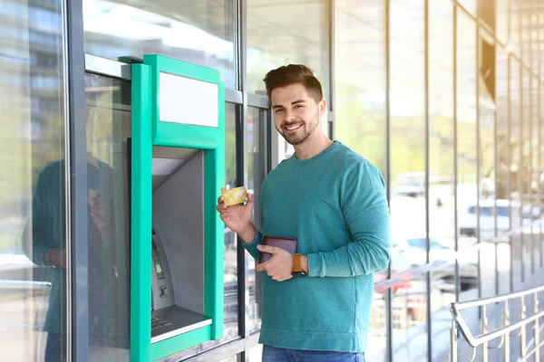 Junger Mann mit Kreditkarte in der Nähe von Geldautomaten — Stockfoto