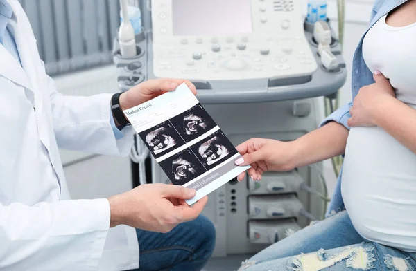 Médico mostrando imagens de ultra-som do bebê para futura mãe na clínica, close-up — Fotografia de Stock