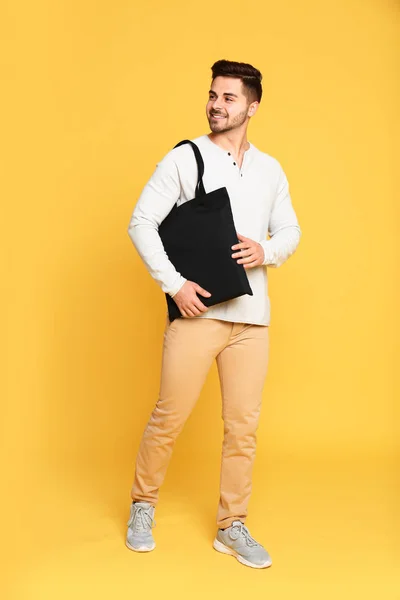 Ritratto a figura intera di giovane uomo con eco bag su sfondo giallo — Foto Stock