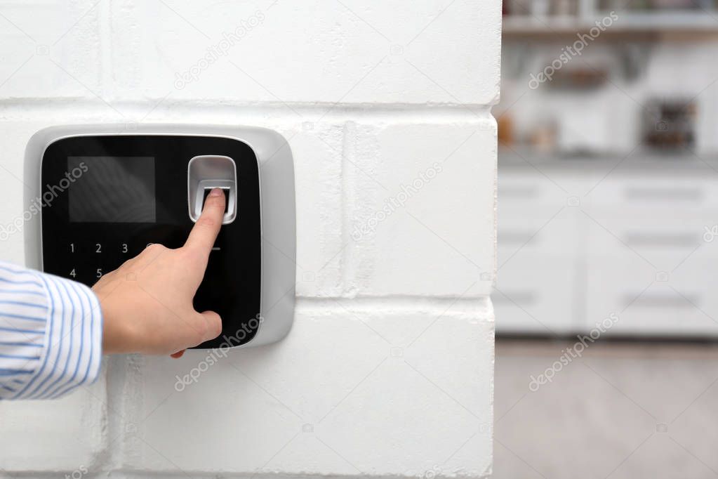 Woman scanning fingerprint on alarm system at home, closeup. Space for text