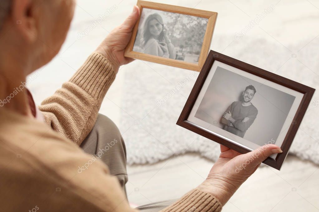 Elderly woman with framed photos at home