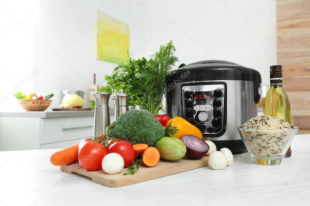 Modern multi cooker and products on kitchen table