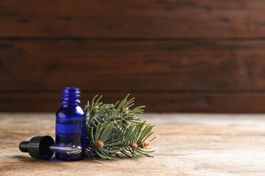 Ahşap masa üzerinde kozalaklı uçucu yağ şişesi ile Kompozisyon. Metin için alan