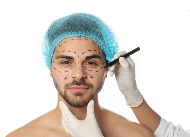 Doktor beyaz arka plan karşı kozmetik cerrahi operasyon için adamın yüzüne işaretler çizim