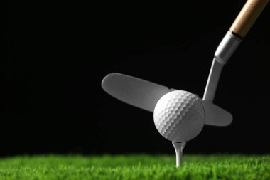 Siyah arka plan, metin alanı karşı yapay çim üzerinde kulüp ile golf topu vurmak