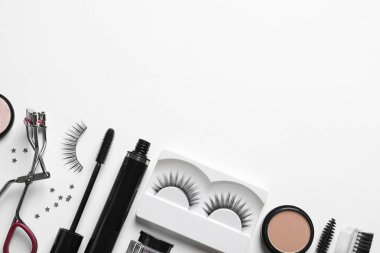 Beyaz arka planda yanlış kirpik ve diğer makyaj ürünleri ile kompozisyon, üst görünüm
