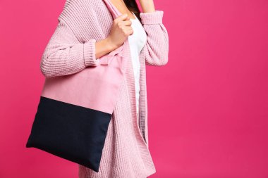 Pembe arka planda tekstil çantası olan genç kadın, yakın çekim. Metin için alan