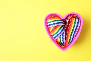 Kalp şeklinde kalıp ve renkli arka plan üzerinde parlak gökkuşağı şerit, metin için boşluk ile üst görünüm. Eşcinsel topluluğunun sembolü