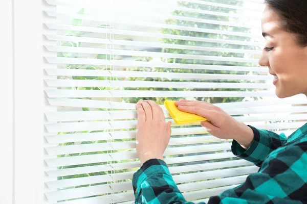 Mooie vrouw schoonmaken raam jaloezieën met Rag binnenshuis — Stockfoto